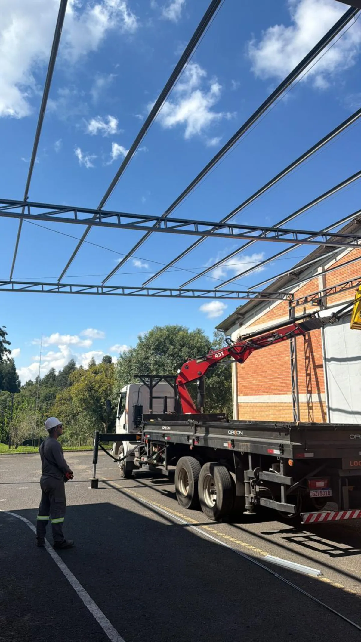 Operário com EPI ao lado de caminhão-guindaste da Orion
